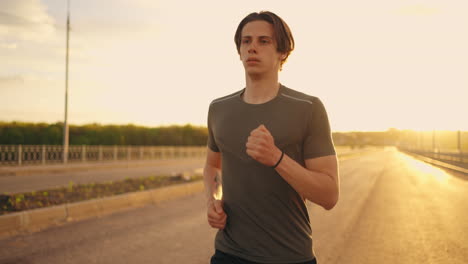 medium-portrait-of-running-man-in-sunny-morning-athlete-is-jogging-on-empty-road-training-alone